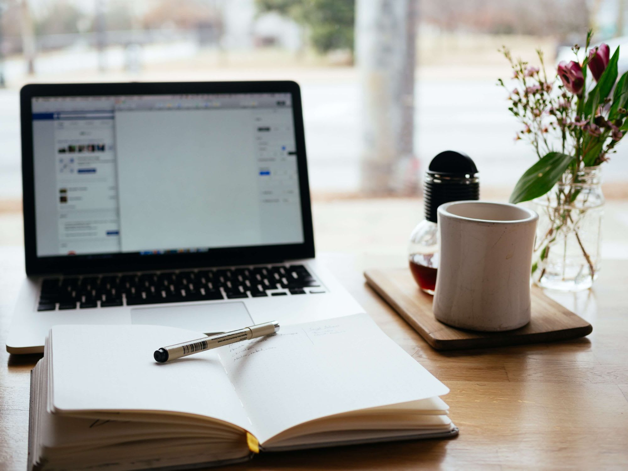 laptop with writing journal in front and coffee