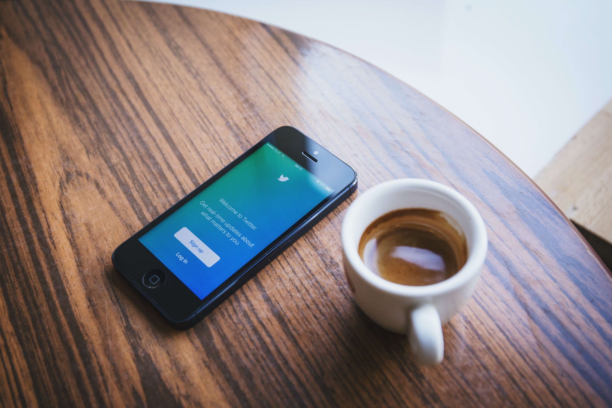 Phone with twitter logo and a coffee
